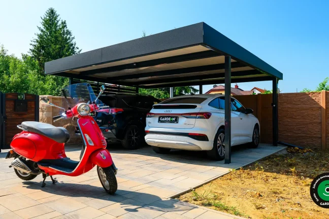 Čierny prístrešok pre dve autá s kontrastnou tehlovou stenou a oplotením.