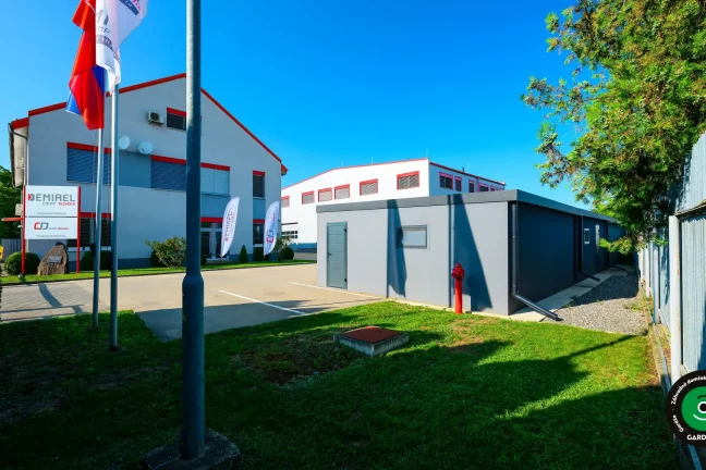 Garáže v areáli firmy s administratívnou budovou v pozadí.