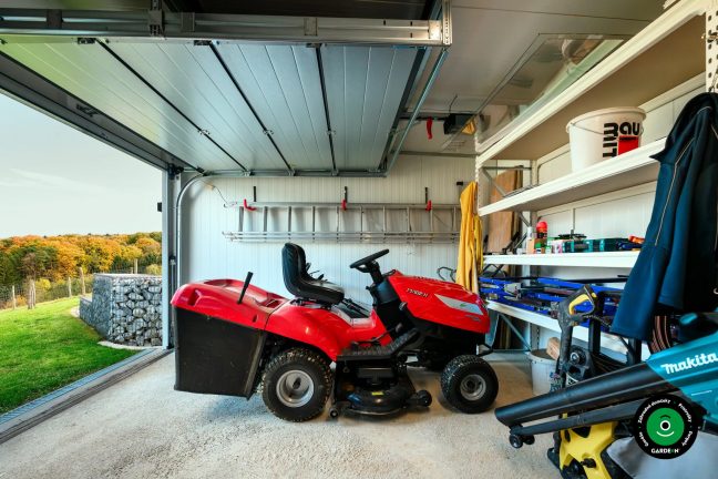 Detail garáže s policami, náradím a červenou záhradnou kosačkou