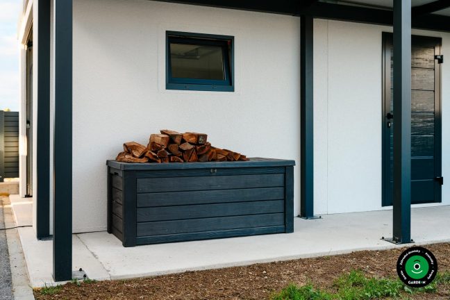 Drevený box s uloženým drevom pod prístreškom