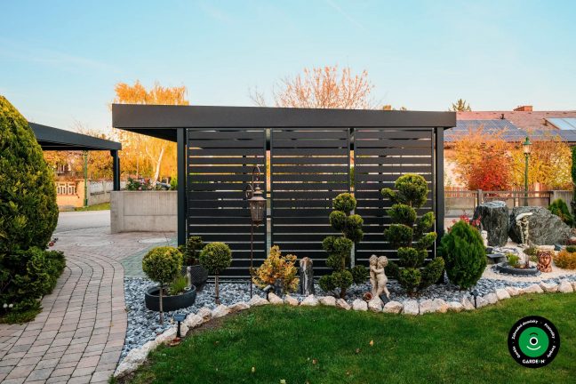 Bočná stena prístrešku pri okrasných drevinách a kamienkoch